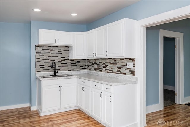 1015 Maiden Ln, Springfield, OH 45504 - kitchen featuring a sink, light countertops, light wood finished floors, decorative backsplash, and white cabinetry