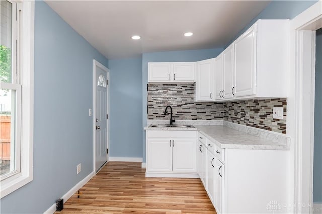 1015 Maiden Ln, Springfield, OH 45504 - kitchen with a sink, light countertops, tasteful backsplash, light wood-style floors, and white cabinetry