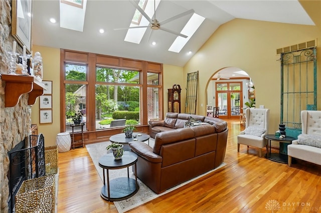 1129 Green Tree Rd, Centerville, OH 45429 - living area featuring a skylight, arched walkways, a stone fireplace, light wood-type flooring, and high vaulted ceiling