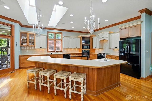 1129 Green Tree Rd, Centerville, OH 45429 - kitchen featuring black appliances, a chandelier, a skylight, a spacious island, and ornamental molding