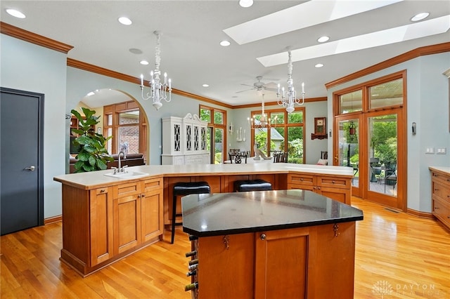 1129 Green Tree Rd, Centerville, OH 45429 - kitchen with a center island with sink, a sink, a skylight, ornamental molding, and light wood finished floors