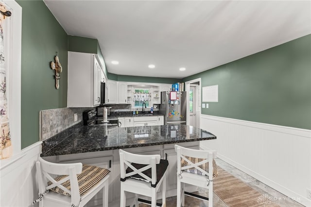 1012 W Sparrow Rd, Springfield, OH 45502 - kitchen with freestanding refrigerator, a wainscoted wall, range with electric cooktop, a peninsula, and a sink