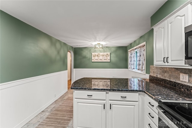 1012 W Sparrow Rd, Springfield, OH 45502 - kitchen with a peninsula, white cabinets, arched walkways, dark stone countertops, and decorative backsplash