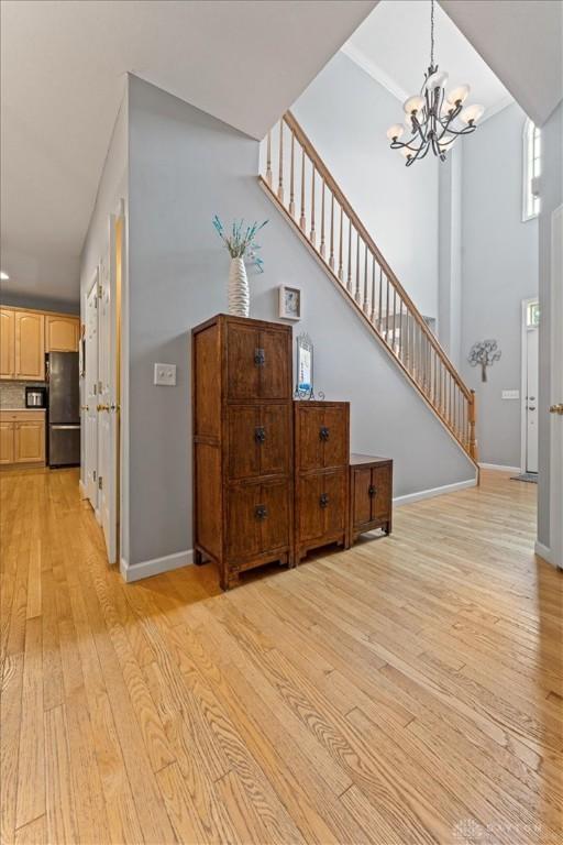 1422 Shawnee Run Dr, Maineville, OH 45039 - living area with a chandelier, light wood-type flooring, stairs, a high ceiling, and baseboards