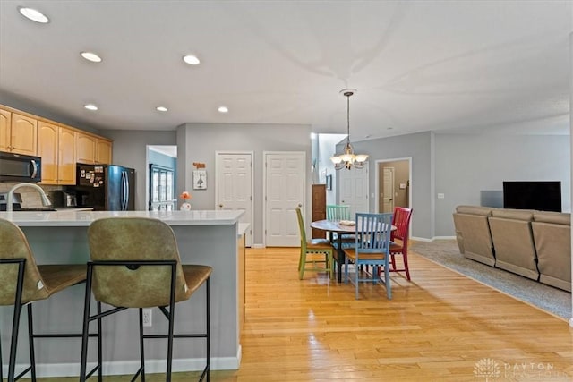 1422 Shawnee Run Dr, Maineville, OH 45039 - kitchen with black appliances, a kitchen bar, a chandelier, light countertops, and recessed lighting