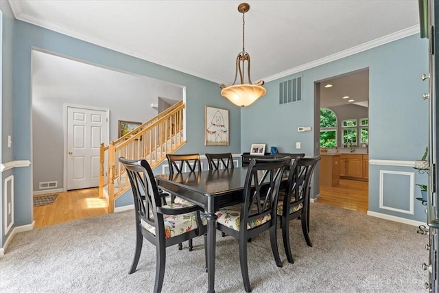 1422 Shawnee Run Dr, Maineville, OH 45039 - dining area featuring light colored carpet, stairway, crown molding, baseboards, and light wood-type flooring