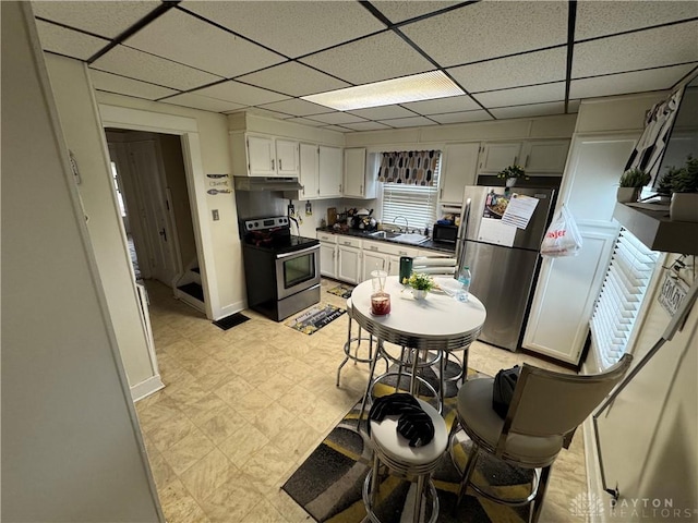 1606 W Grand Ave, Dayton, OH 45402 - kitchen featuring appliances with stainless steel finishes, a sink, under cabinet range hood, a drop ceiling, and dark countertops