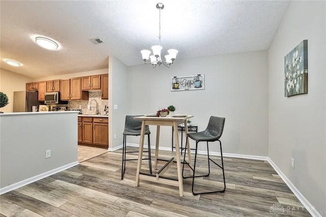1690 Piper Ln Unit 206, Washington Twp, OH 45440 - dining area with a textured ceiling, light wood-style floors, a chandelier, and baseboards
