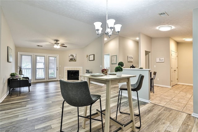 1690 Piper Ln Unit 206, Washington Twp, OH 45440 - kitchen with light wood finished floors, vaulted ceiling, a tiled fireplace, a ceiling fan, and a textured ceiling