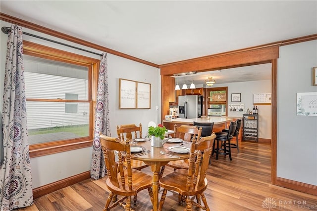 107 S High St, Arcanum, OH 45304 - dining space featuring baseboards, light wood finished floors, crown molding, and healthy amount of natural light