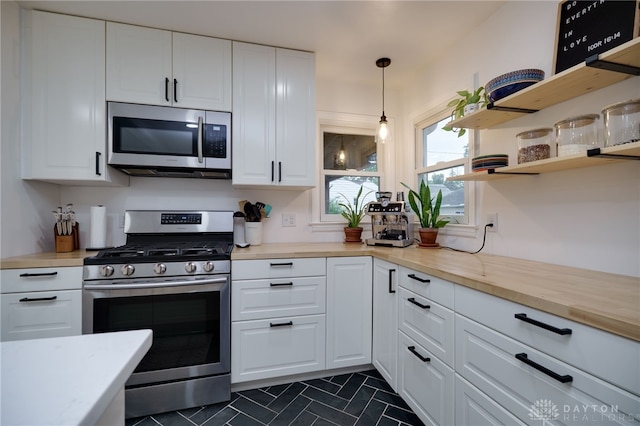 3227 Mirimar St, Dayton, OH 45409 - kitchen featuring stainless steel appliances, light countertops, white cabinets, and hanging light fixtures