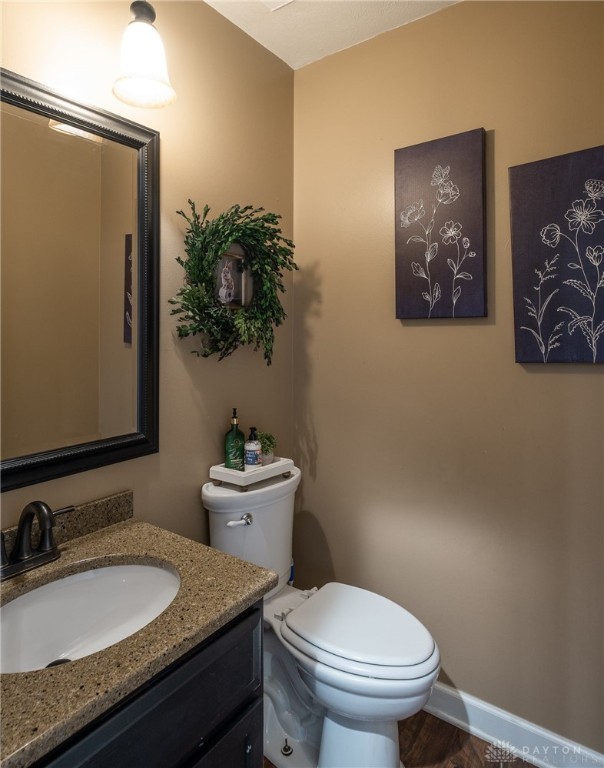 2155 Shenandoah Dr, Troy, OH 45373 - half bathroom featuring toilet, vanity, wood finished floors, and baseboards