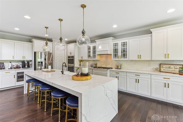 3886 Hudson Hills Ln, Mason, OH 45040 - kitchen featuring appliances with stainless steel finishes, white cabinets, an island with sink, tasteful backsplash, and crown molding