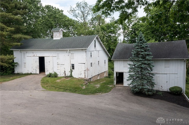 5894 Hamilton Lebanon Rd, Monroe, OH 45044 - view of front of property with an outbuilding, a chimney, a shingled roof, and board and batten siding