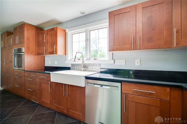 5894 Hamilton Lebanon Rd, Monroe, OH 45044 - kitchen featuring stainless steel appliances, a sink, brown cabinets, dark tile patterned floors, and dark countertops