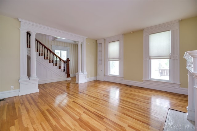 5894 Hamilton Lebanon Rd, Monroe, OH 45044 - unfurnished living room featuring light wood finished floors, decorative columns, stairway, and plenty of natural light