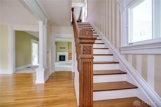 5894 Hamilton Lebanon Rd, Monroe, OH 45044 - stairway featuring wood finished floors, wallpapered walls, ornate columns, a fireplace, and baseboards