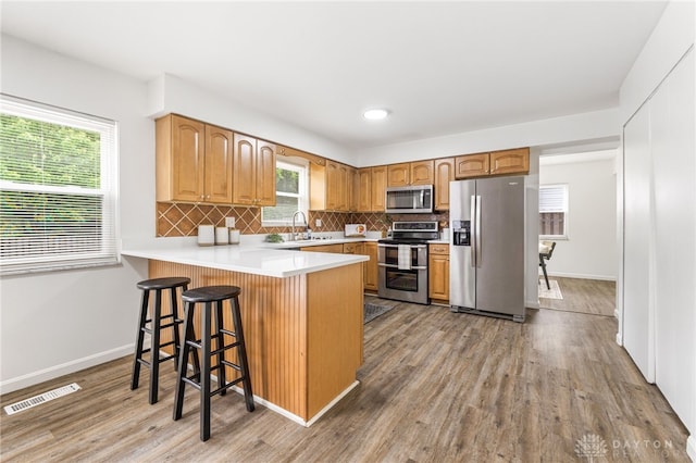 4513 Silver Oak St, Dayton, OH 45424 - kitchen featuring appliances with stainless steel finishes, a sink, a peninsula, wood finished floors, and tasteful backsplash