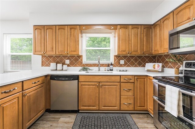 4513 Silver Oak St, Dayton, OH 45424 - kitchen with stainless steel appliances, a sink, light wood-style floors, light countertops, and brown cabinets