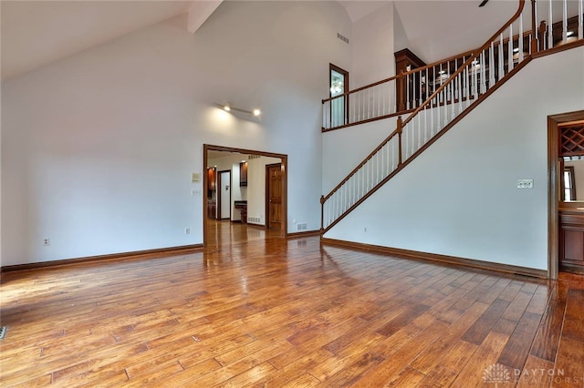 7299 Country Club Ln, West Chester, OH 45069 - unfurnished living room featuring high vaulted ceiling, wood-type flooring, stairs, and baseboards