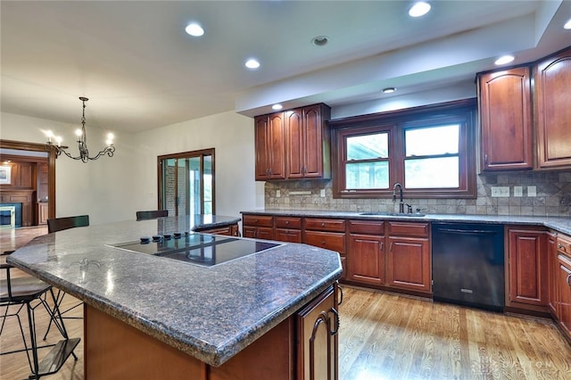7299 Country Club Ln, West Chester, OH 45069 - kitchen with black appliances, a center island, a breakfast bar, decorative backsplash, and light wood-style floors