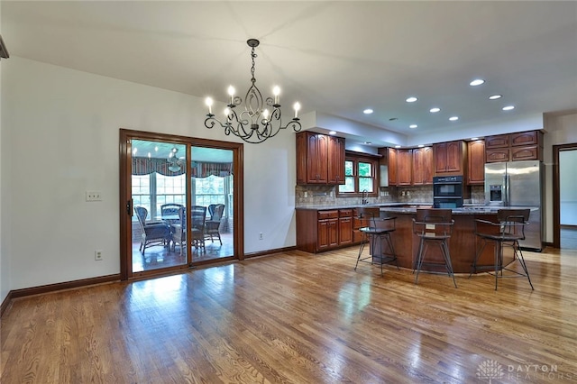 7299 Country Club Ln, West Chester, OH 45069 - kitchen with stainless steel fridge, a chandelier, light wood-style flooring, decorative backsplash, and recessed lighting