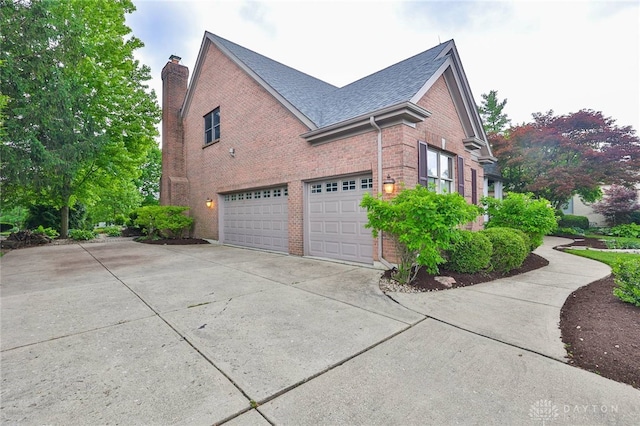 7299 Country Club Ln, West Chester, OH 45069 - view of property exterior with driveway, a chimney, brick siding, and an attached garage