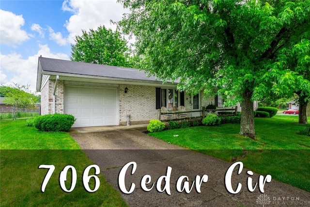 706 Cedar Cir, Eaton, OH 45320 - view of front of home featuring an attached garage, driveway, covered porch, and brick siding