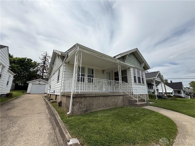 1805 Fauver Ave, Dayton, OH 45420 - view of front of house featuring covered porch, an outdoor structure, asphalt driveway, a front lawn, and a garage