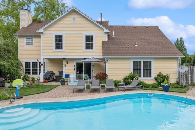 2866 Fence Stone Ct, Dayton, OH 45458 - rear view of house featuring a chimney, an outdoor pool, a patio, and roof with shingles