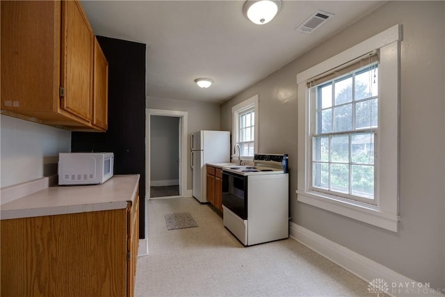 397 Chapman St, Waynesville, OH 45068 - kitchen with white appliances, brown cabinetry, baseboards, light flooring, and light countertops