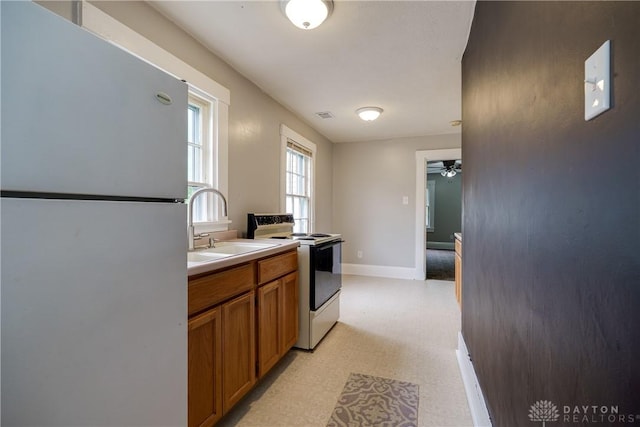 397 Chapman St, Waynesville, OH 45068 - kitchen with white appliances, brown cabinets, light floors, a sink, and a ceiling fan