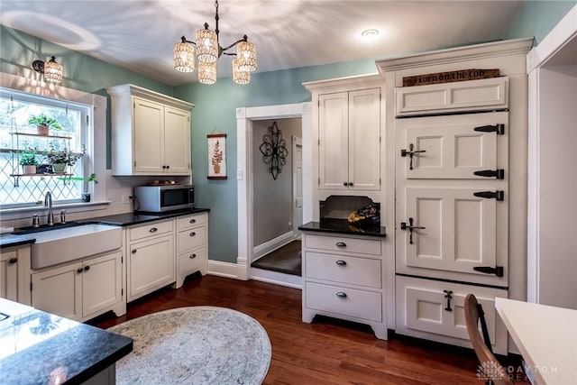 206 Wright Ave, Lebanon, OH 45036 - kitchen featuring stainless steel microwave, a sink, a chandelier, dark wood-type flooring, and dark countertops