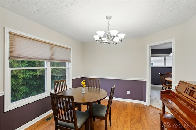 3835 Polo Trace Ct, Bellbrook, OH 45305 - dining area with a chandelier, light wood-type flooring, baseboards, and a textured ceiling