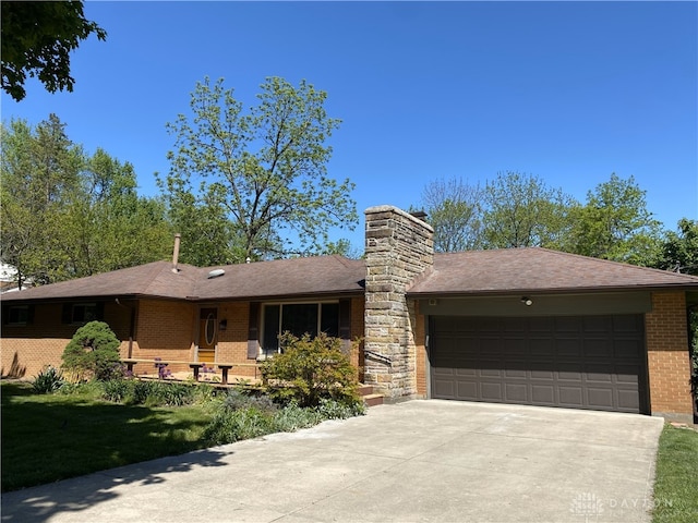 10520 Grand Vista Dr, Dayton, OH 45458 - ranch-style home with brick siding, an attached garage, a chimney, driveway, and a shingled roof