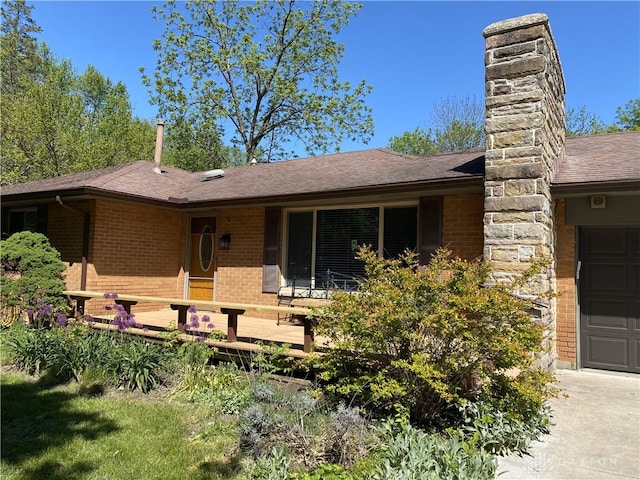 10520 Grand Vista Dr, Dayton, OH 45458 - view of front of house featuring brick siding, a garage, a shingled roof, a chimney, and a wooden deck