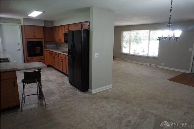 10520 Grand Vista Dr, Dayton, OH 45458 - kitchen with black appliances, a chandelier, brown cabinetry, hanging light fixtures, and a kitchen bar