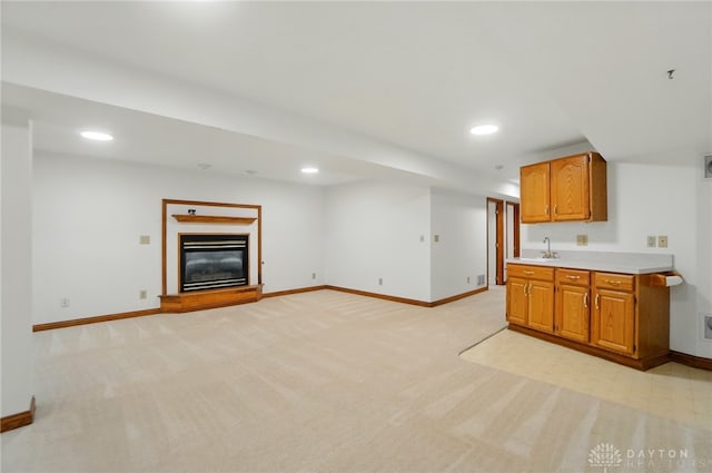 220 Fivepines Ct, Englewood, OH 45315 - unfurnished living room with light colored carpet, baseboards, recessed lighting, a glass covered fireplace, and a sink