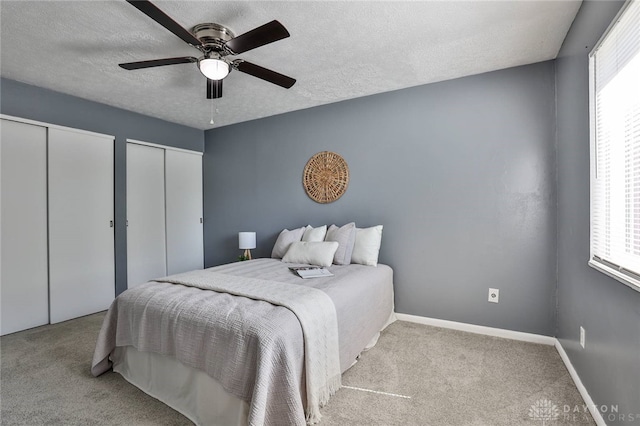 5695 E Coach Dr Unit E, Kettering, OH 45440 - carpeted bedroom featuring multiple closets, multiple windows, a textured ceiling, a ceiling fan, and baseboards