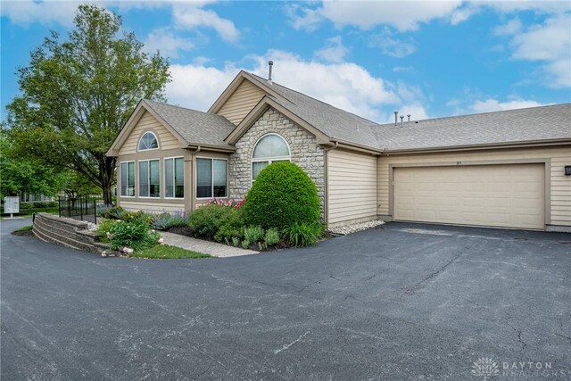 91 Villa Pointe Dr, Springboro, OH 45066 - view of front facade with asphalt driveway, an attached garage, stone siding, and a shingled roof