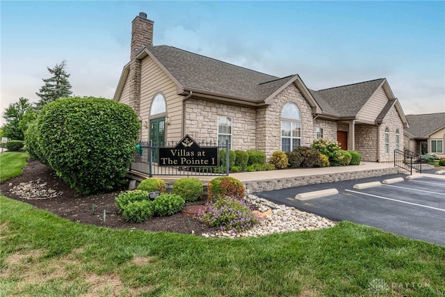 91 Villa Pointe Dr, Springboro, OH 45066 - view of side of property featuring stone siding, uncovered parking, a chimney, and roof with shingles