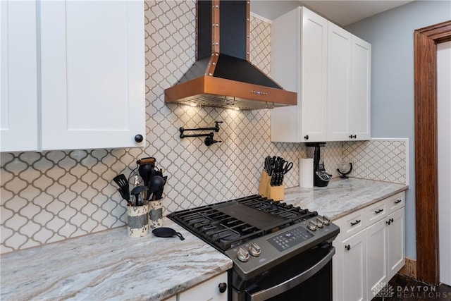 25 La Belle St, Dayton, OH 45403 - kitchen with wall chimney range hood, stainless steel gas range, white cabinets, light stone counters, and tasteful backsplash