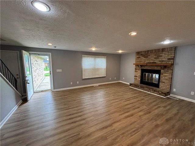 5901 Timbergate Trl, Dayton, OH 45424 - unfurnished living room with a textured ceiling, healthy amount of natural light, wood finished floors, baseboards, and a brick fireplace