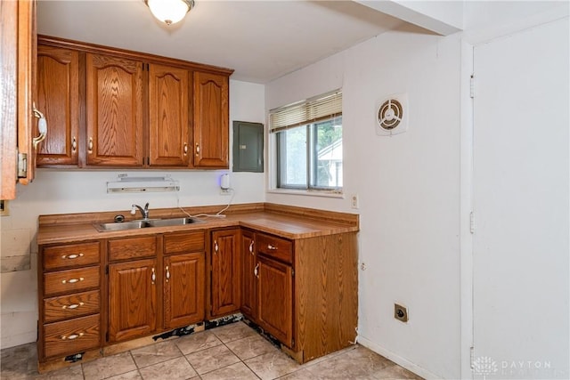 5501 Harshmanville Rd, Dayton, OH 45424 - kitchen featuring electric panel, brown cabinetry, a sink, and light tile patterned flooring