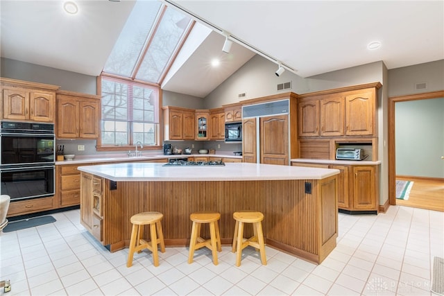 514 Shambord Cir, Kettering, OH 45429 - kitchen featuring black appliances, light countertops, a kitchen bar, a center island, and lofted ceiling
