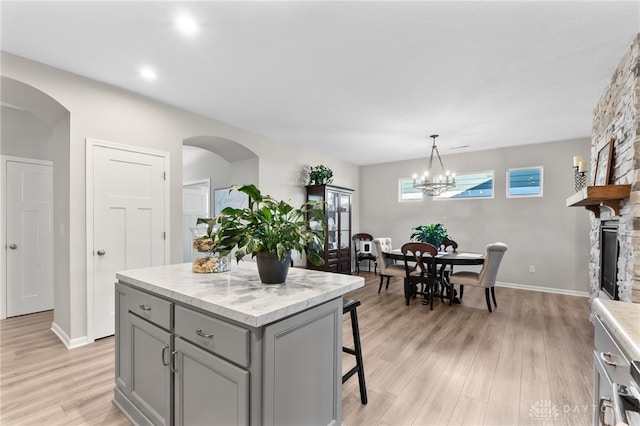 4978 Renaissance Park Dr, Middletown, OH 45005 - kitchen with gray cabinets, light countertops, light wood finished floors, a kitchen breakfast bar, and a chandelier