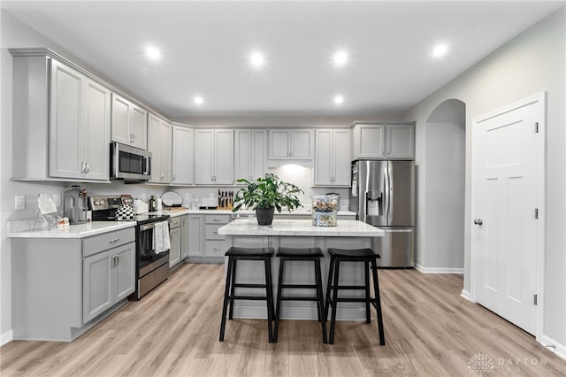 4978 Renaissance Park Dr, Middletown, OH 45005 - kitchen with stainless steel appliances, gray cabinetry, a breakfast bar, light wood-style flooring, and arched walkways