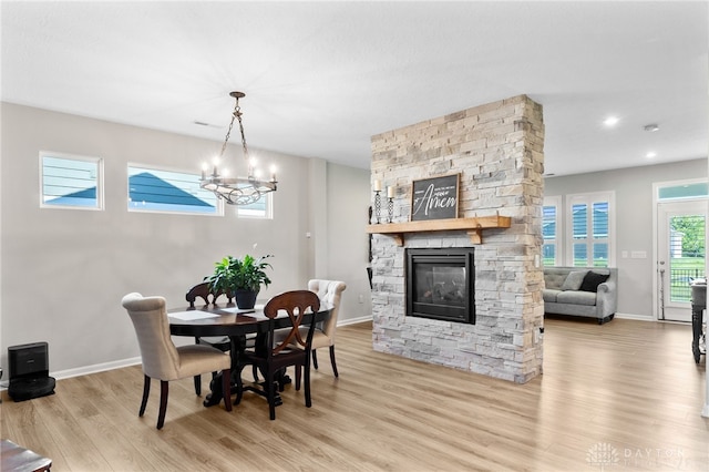 4978 Renaissance Park Dr, Middletown, OH 45005 - dining space with light wood finished floors, a stone fireplace, baseboards, and a chandelier