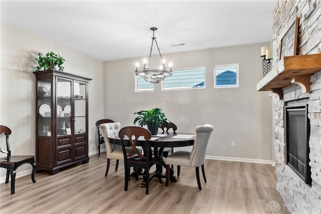 4978 Renaissance Park Dr, Middletown, OH 45005 - dining space with a stone fireplace, light wood-type flooring, a chandelier, and baseboards