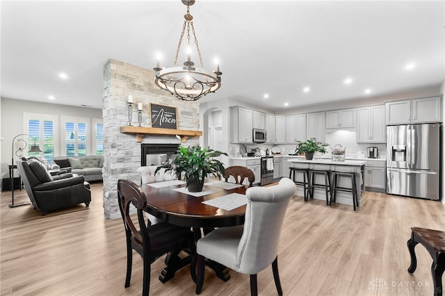4978 Renaissance Park Dr, Middletown, OH 45005 - dining space with light wood-type flooring, a chandelier, a fireplace, recessed lighting, and arched walkways